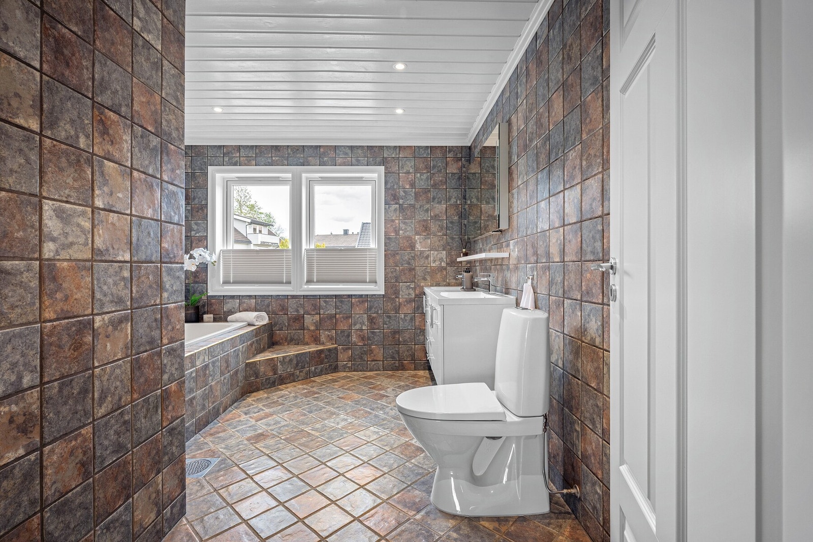 Badet i 2. etasje er romslig og praktisk innredet med flislagte overflater, gulvvarme, servantinnredning med god oppbevaringsplass, frittstående toalett og innmurt badekar. Galleribilde