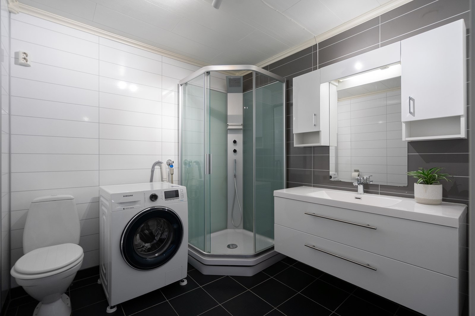 Badet innredning med heldekkende servantskap, overskap og speil., dusjkabinett, toalett og opplegg for vaskemaskin. Galleribilde