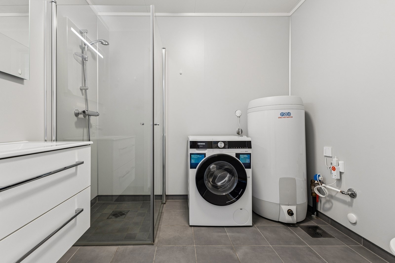 Praktisk kombinert baderom og vaskerom med elektrisk gulvvarme, opplegg for vaskemaskin og en 200-liters varmtvannsbereder. Galleribilde