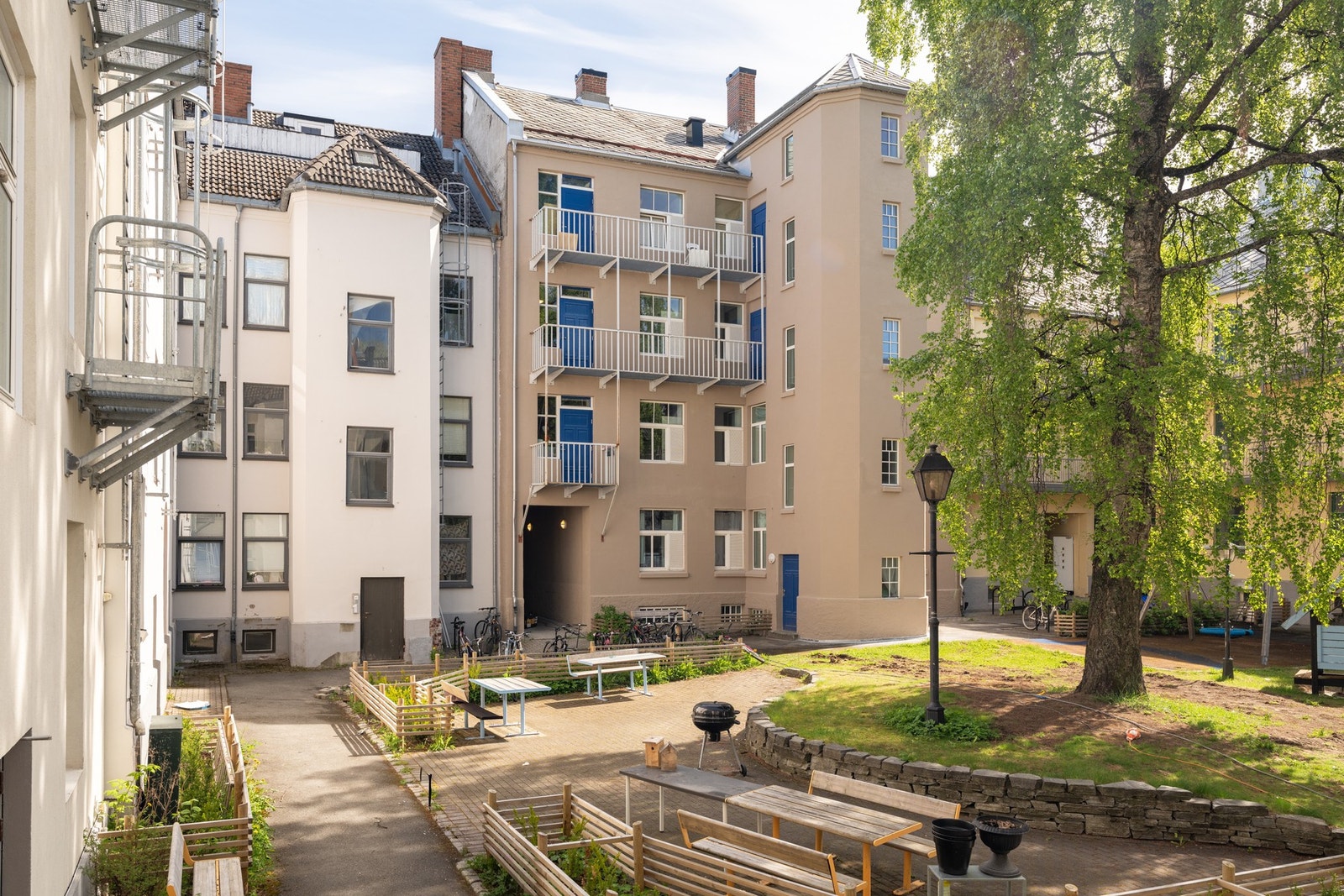 På baksiden er det et stort beplantet fellesareal med benker. Galleribilde