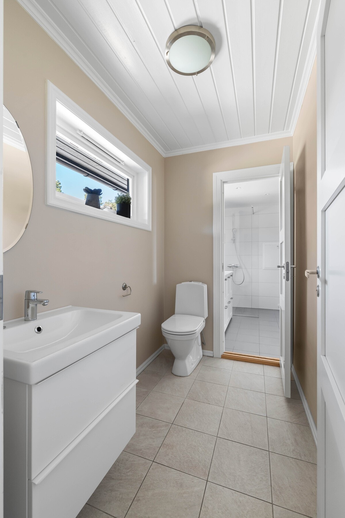 Lyst og moderne wc med praktisk servant og vindu for naturlig lys. Galleribilde