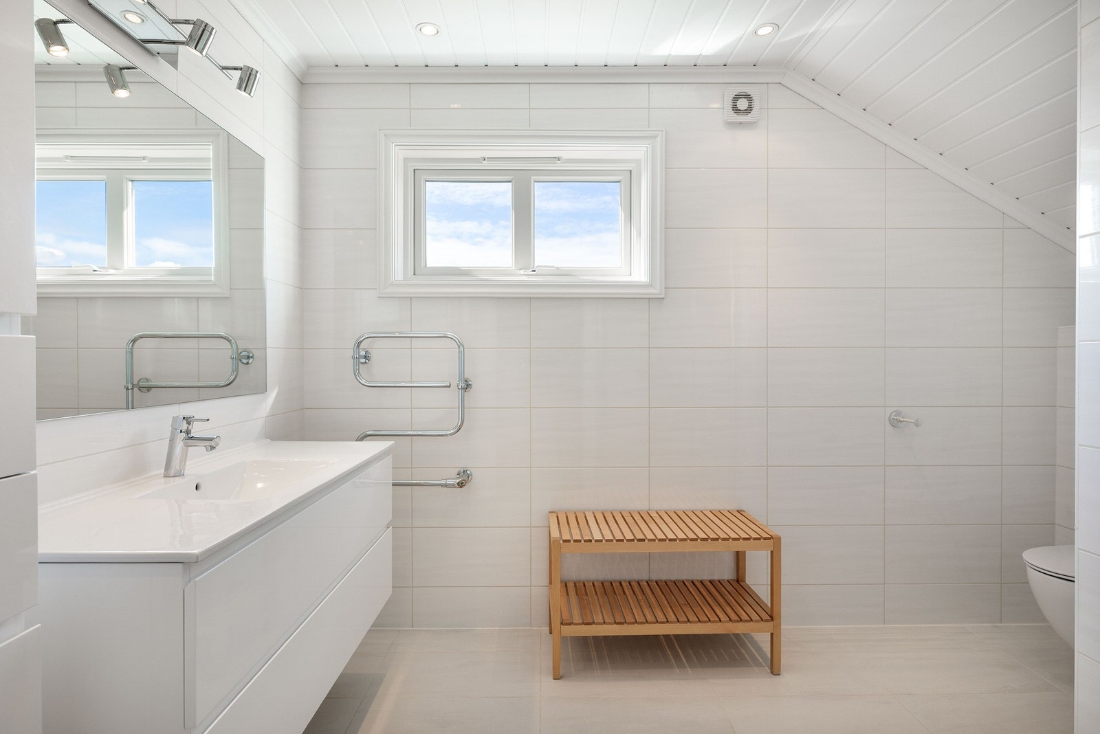 Lyst, flislagt bad med nedfelt servant i innredning, vegghengt toalett og dusj. Galleribilde