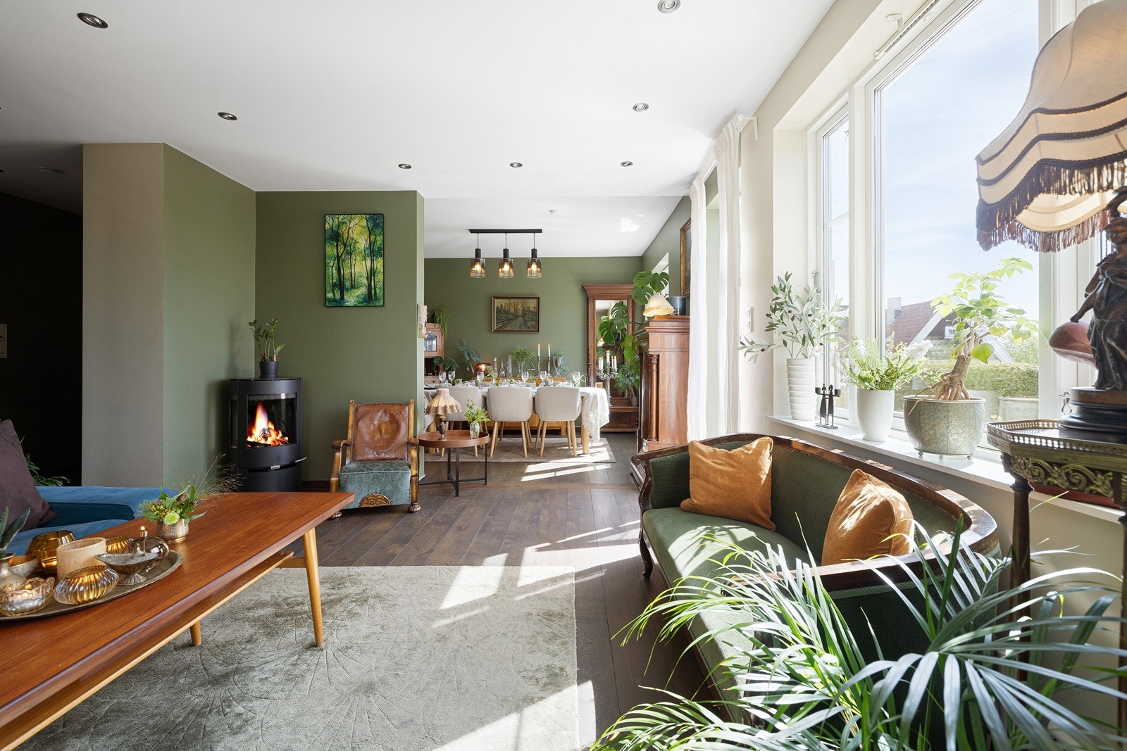 Stor stue med peis og videre inn til spisestuen med flott fjordutsikt Galleribilde