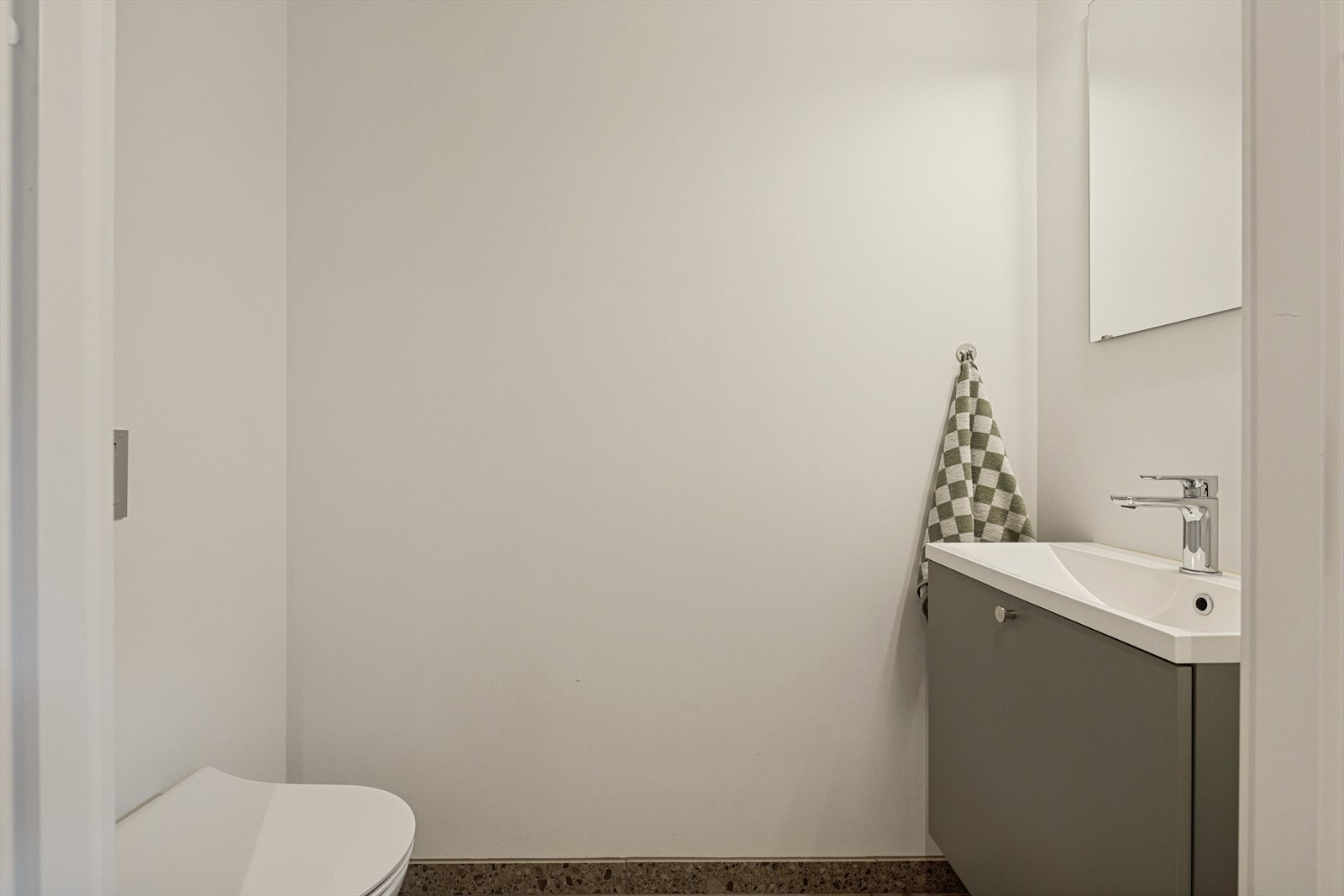 Toalettrommet har fliser på gulv med vannbåren varme. Malte plater på vegg, downlights. Sanitærutstyr bestående av vegghengt toalett og nedfelt servant i servantskap. Galleribilde
