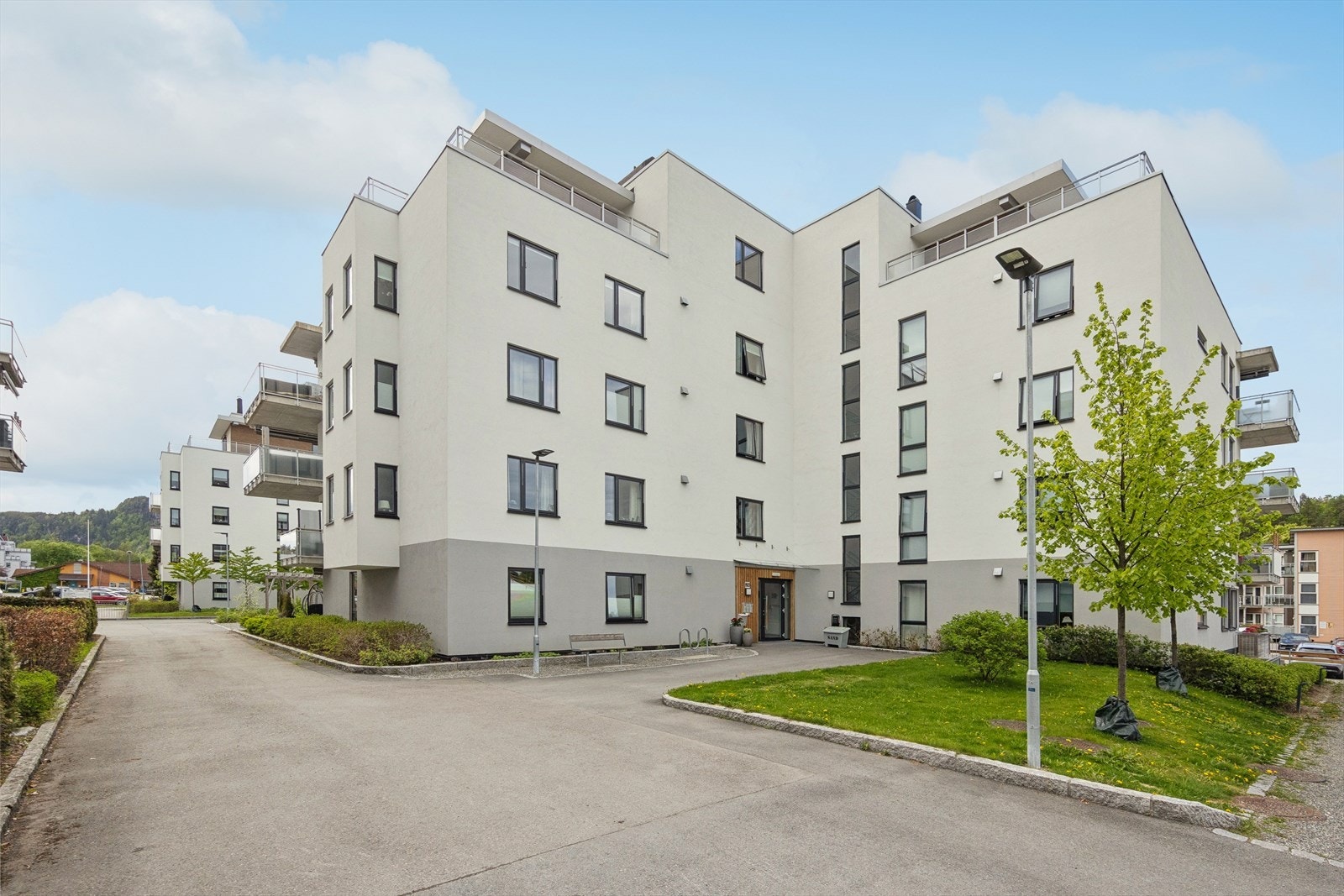 Pent opparbeidet felles tomt med asfalterte adkomst- og internveier. Sittegrupper, gressplen, bed og øvrig beplantning. Galleribilde