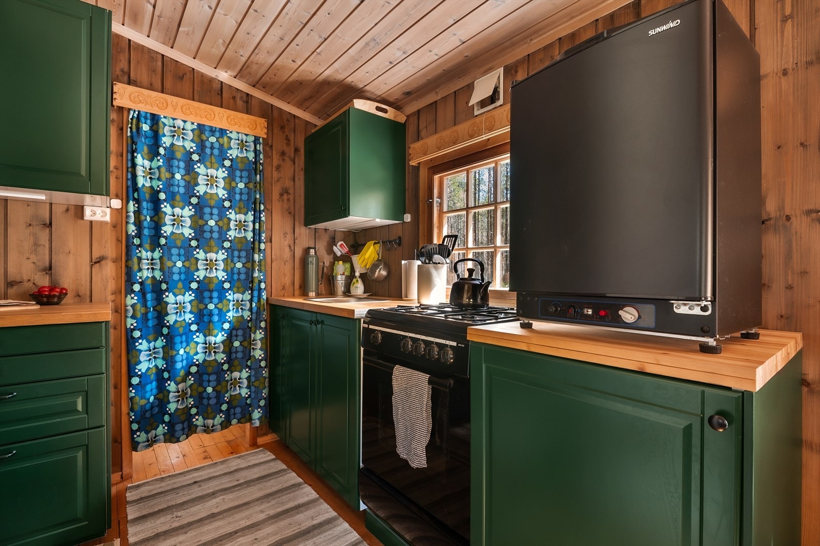 Kjøkkenet har profilerte fronter og benkeplate i laminat, med plass til komfyr og kjøleskap. Fotograf: Petter Aamodt Galleribilde