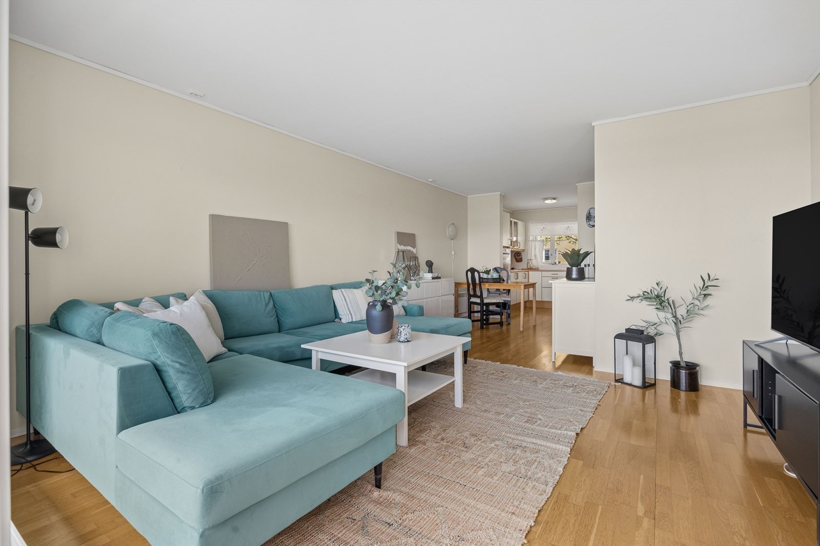 Stuen har god plass til både sofagruppe og spisebord, med gjennomgående parkett og malte, slette vegger. Galleribilde