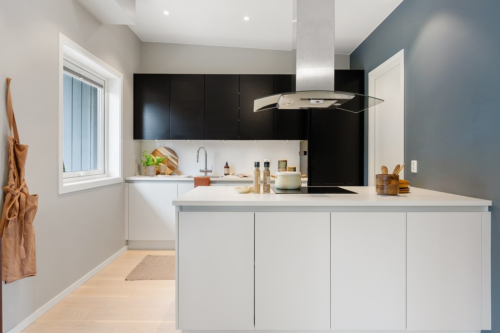 Innredningen består av hvite underskap kombinert med sorte overskap og glatte fronter, noe som gir et stilrent og elegant uttrykk. Galleribilde