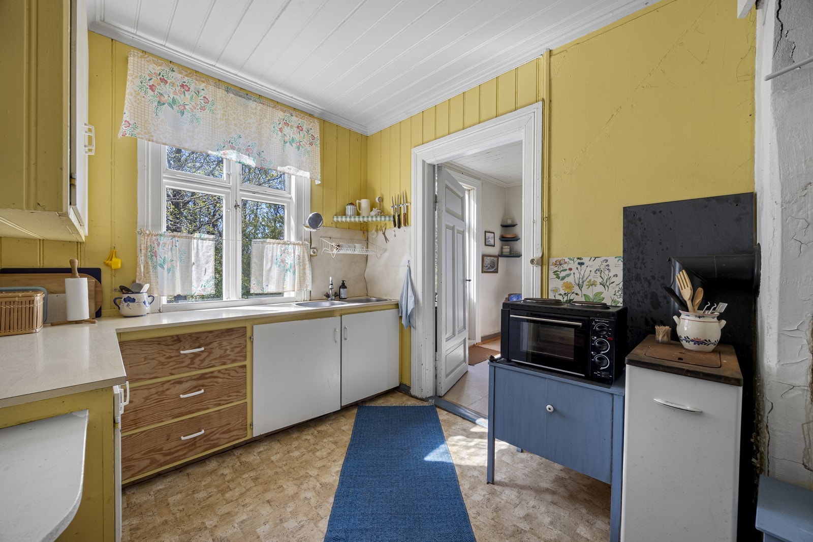 Kjøkkenet har en praktisk benkeplate med dobbel oppvaskkum og overskap for ekstra oppbevaring. Galleribilde