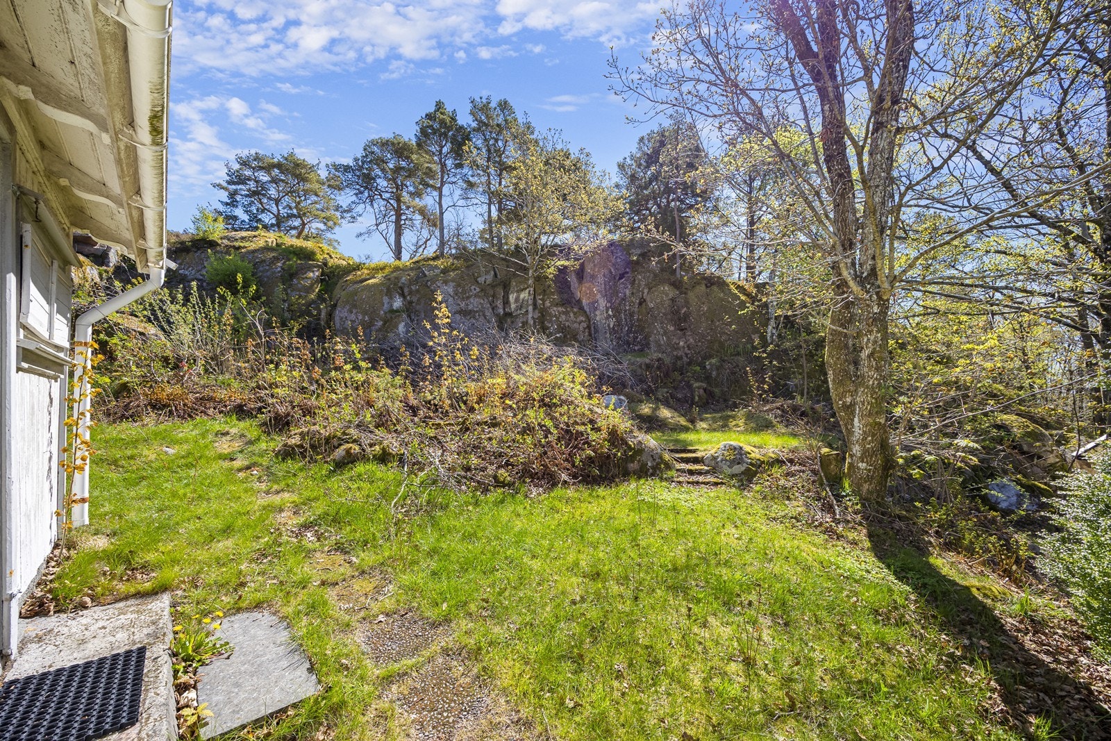 Grønt uteområde med naturlig berglandskap og opparbeidet hage. Galleribilde
