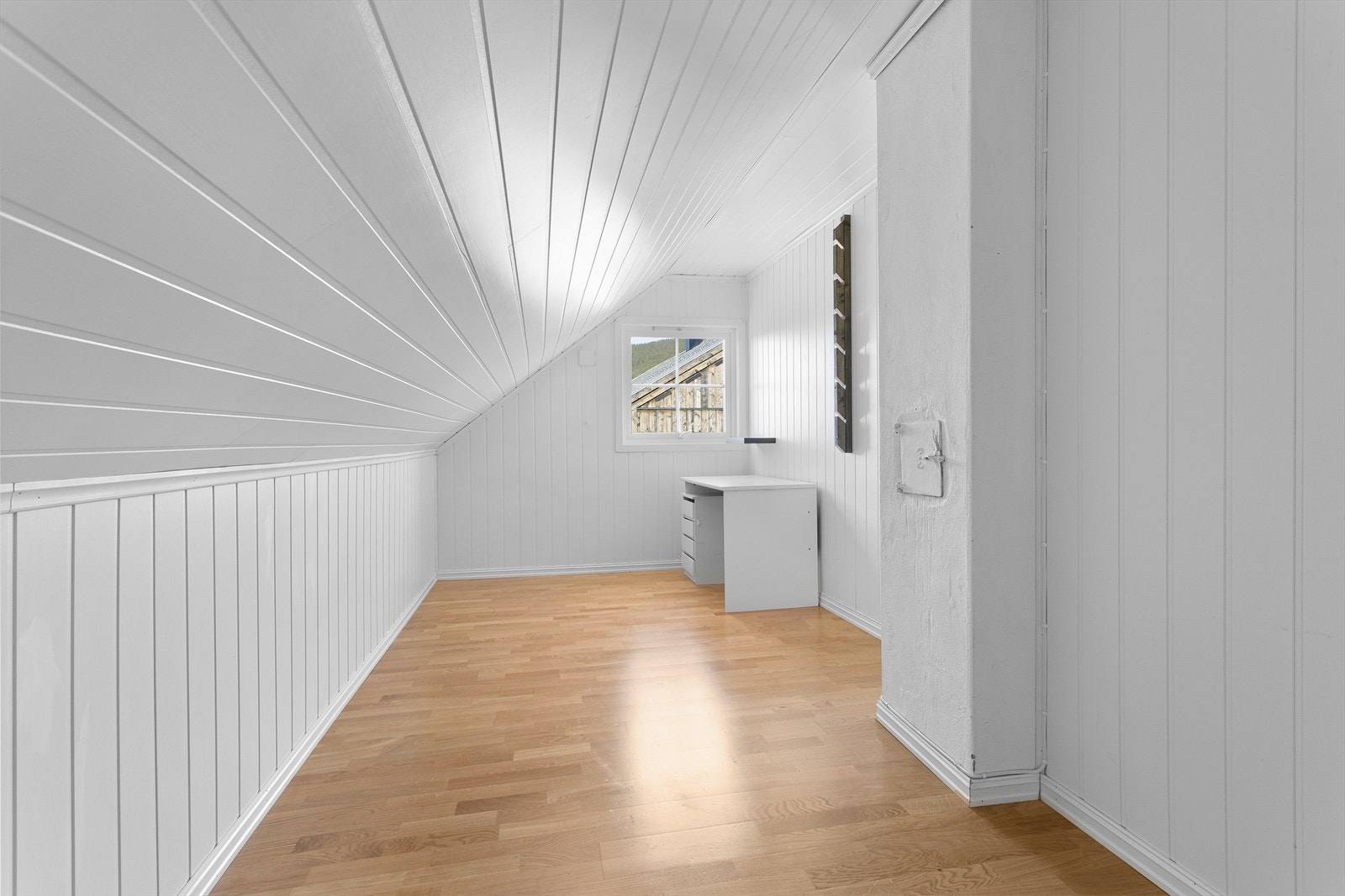 Et lyst rom med panel på vegger og i himling. Etasjen er ikke byggesøkt, og er som følge av dette ikke godkjent for bruk som soveromsareal slik den er innredet i dag. Galleribilde