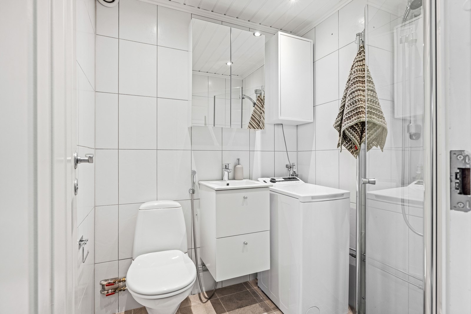 Flislagt bad med varme i gulvet og opplegg for vaskemaskin. Galleribilde