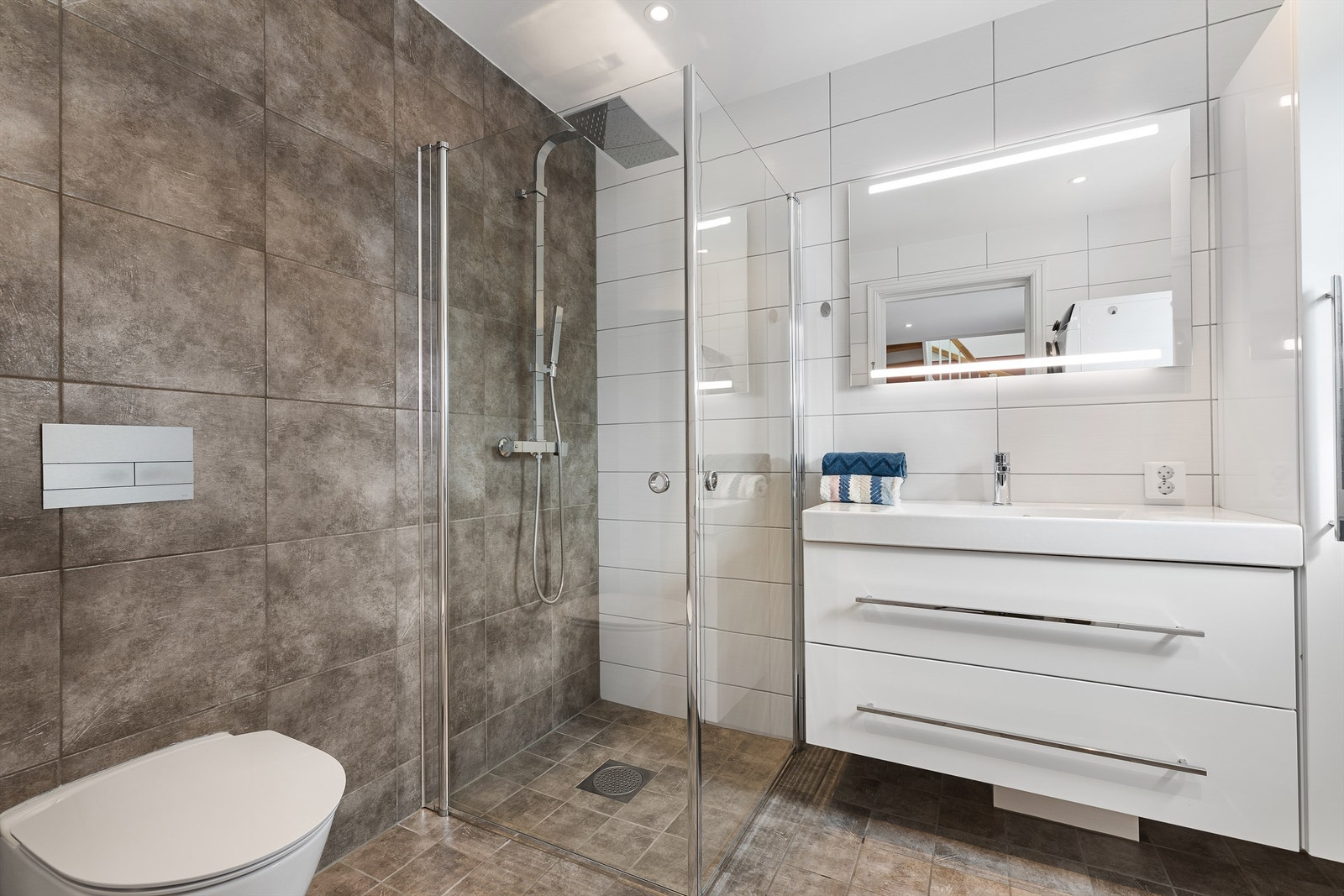 Badet i første etasje er lyst og pent med flislagte overflater og gulvvarme. Galleribilde