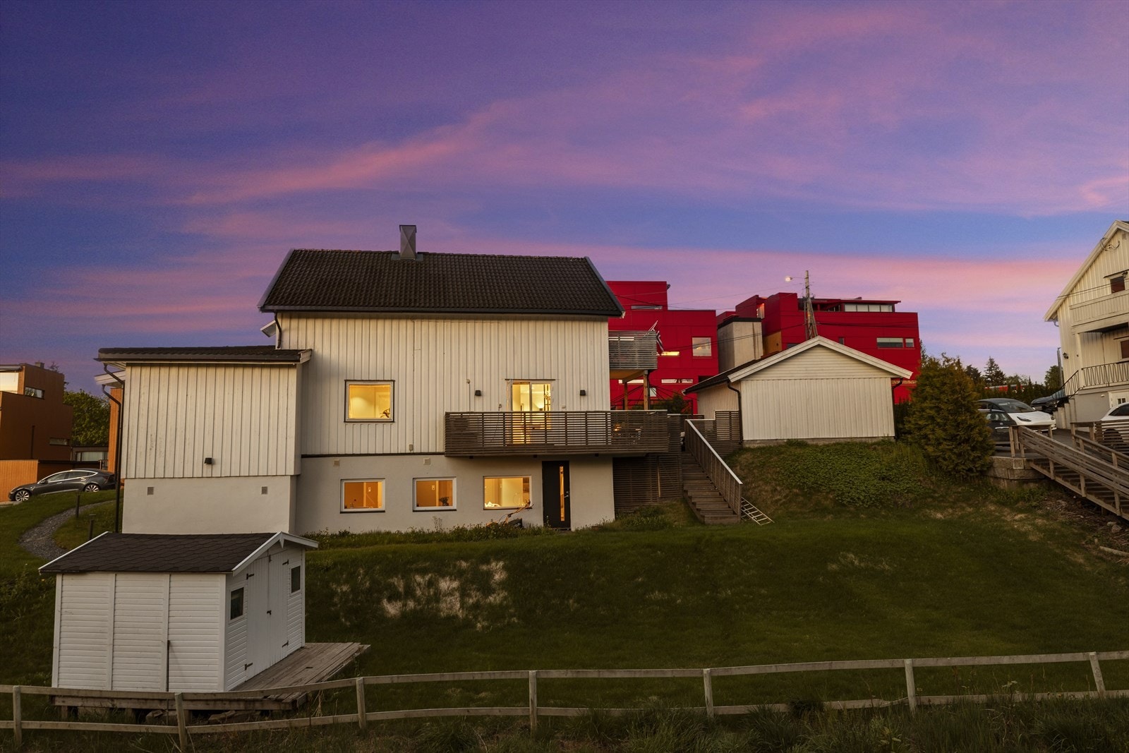 Boligens fasade med malt trepanel og tak tekket med takstein og takplater. Galleribilde