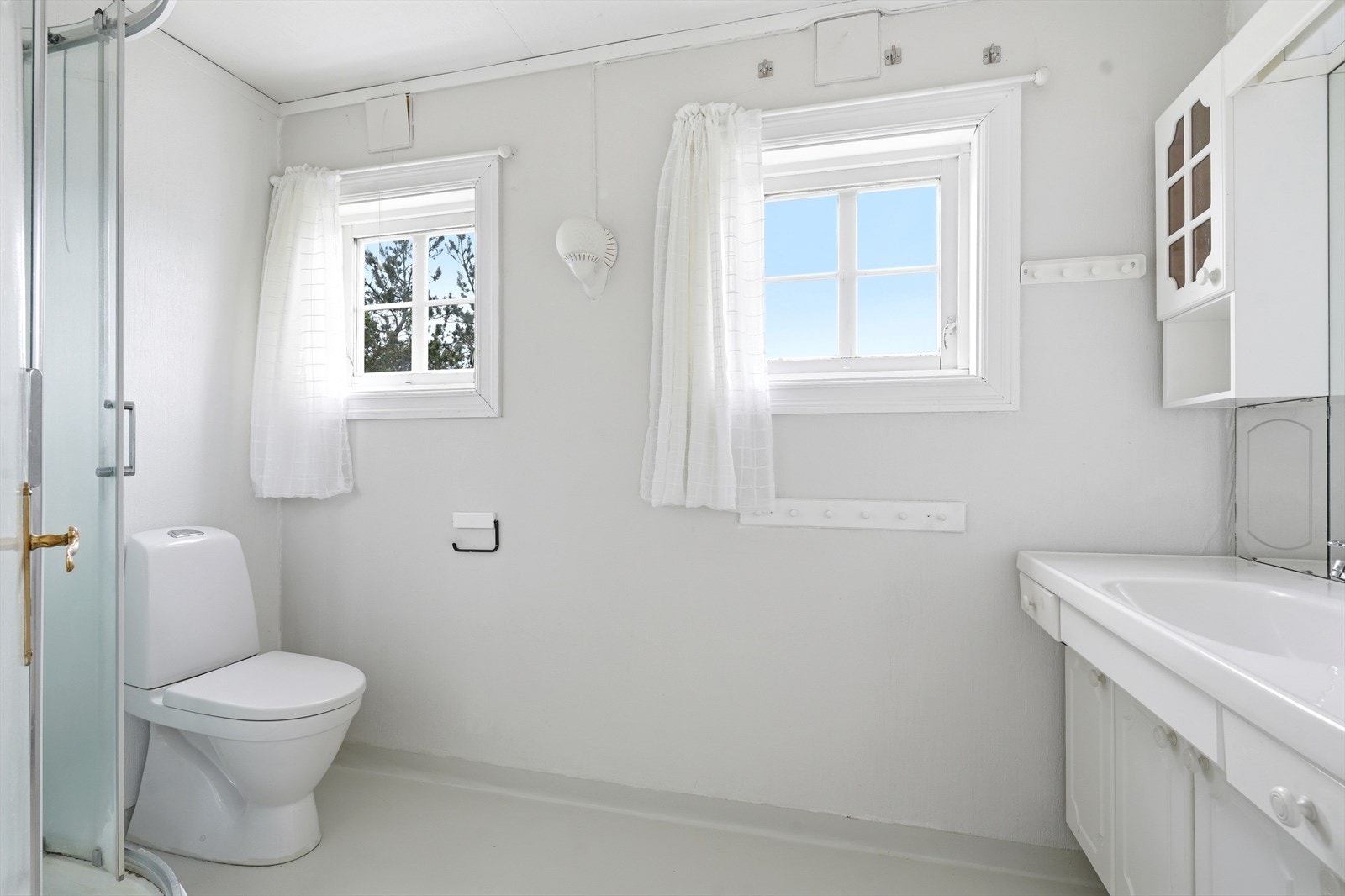 Lyst bad med varme i gulv. Inneholder dusjkabinett, servant med innredning og wc. Galleribilde