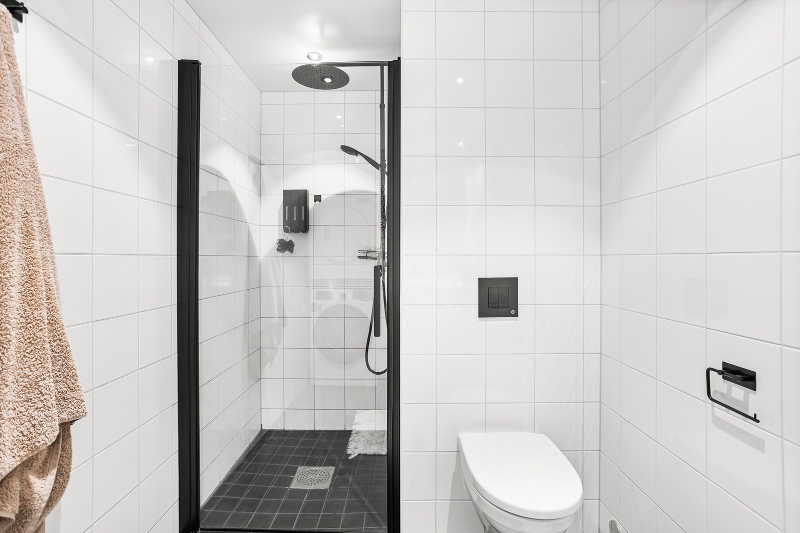 Badet er innredet med servant med underskap, speil, veggehengt toalett, dusjdør og opplegg til vaskemaskin. Galleribilde