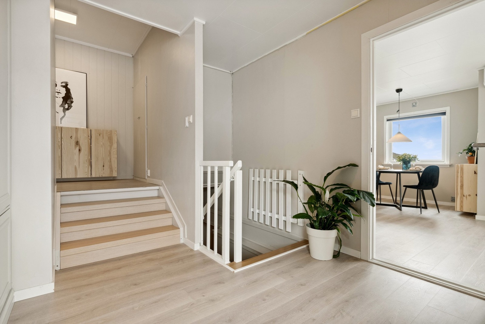 Hallen fungerer som et bindeledd mellom etasjene, med en malt tretrapp og adkomst til boligens oppholdsrom. Galleribilde