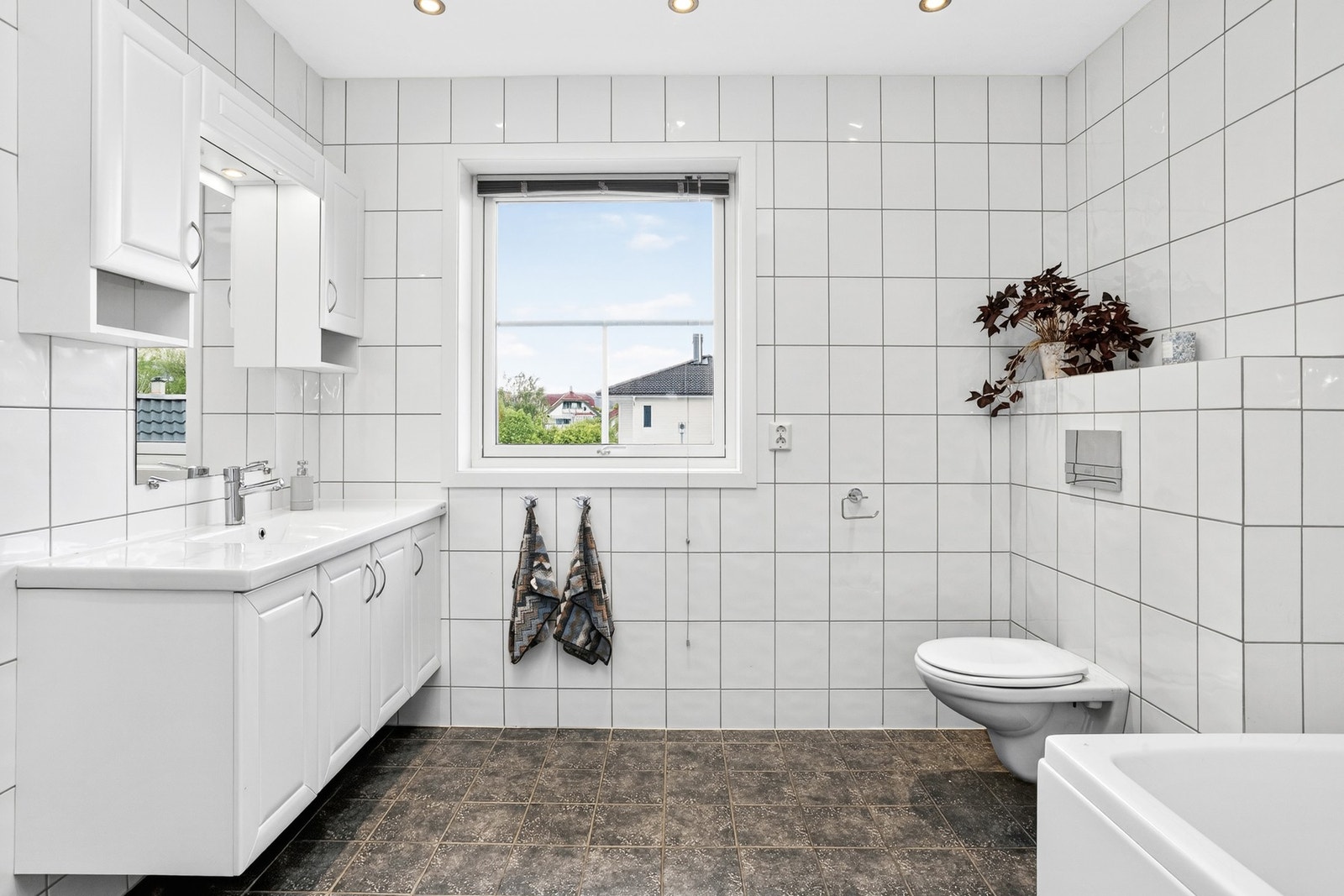 Pent baderom med vegghengt toalett, badekar og servantinnredning Galleribilde