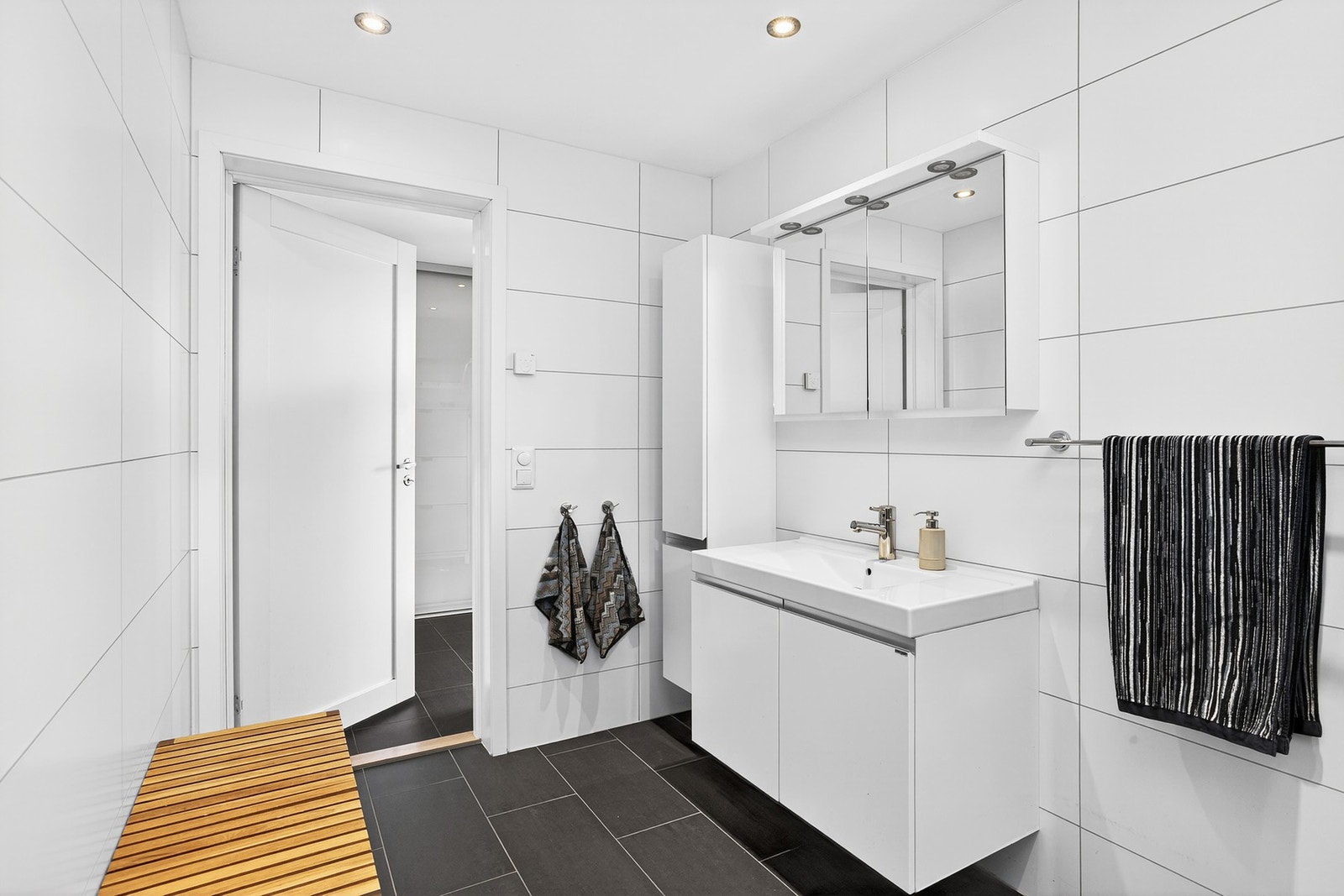 Videre har badet et vegghengt servantskap med slette fronter og ovenpåliggende servant samt ett-greps armatur Galleribilde