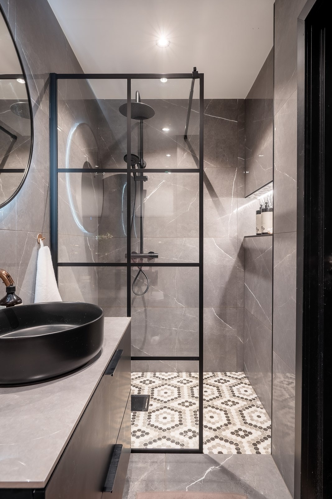 Dusjhørne med glassvegg og regndusj. Servantskap med stein benkeplate og overnpåliggende rund servant samt armatur i messing Galleribilde