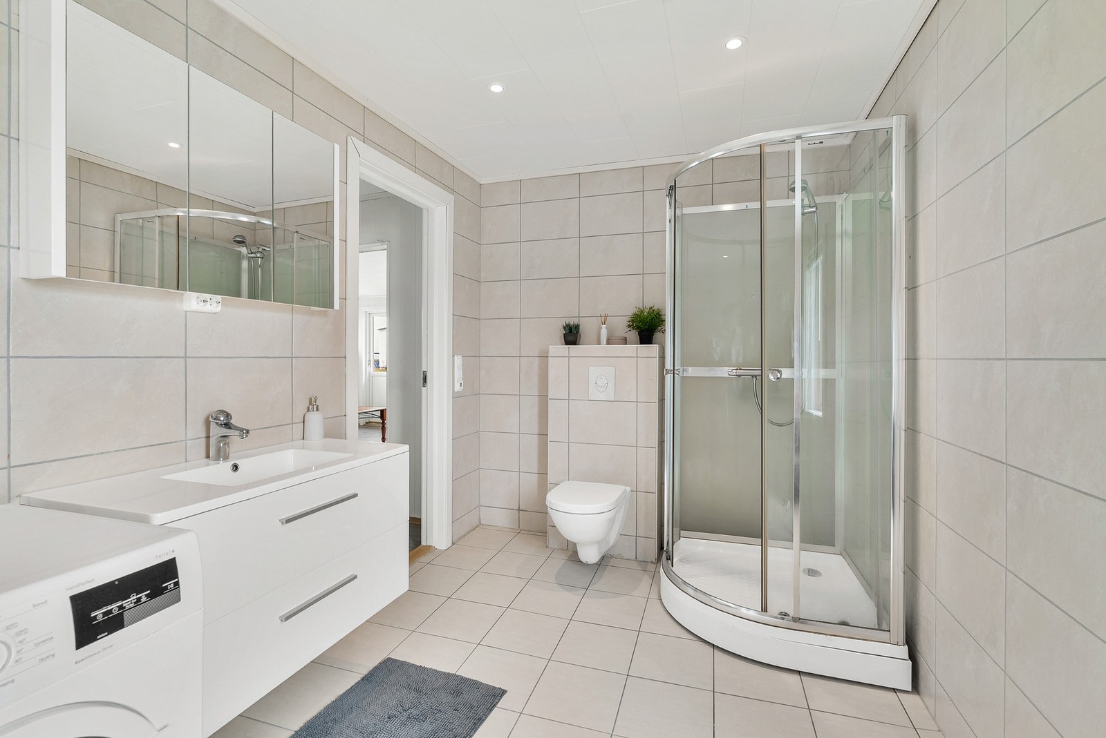 Badet er utstyrt med innredning med nedfelt servant, veggmontert toalett og dusjkabinett. Galleribilde