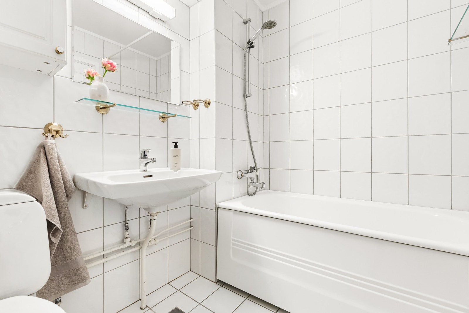 Flislagt bad med varmekabler i gulv. Badet er innredet med vegghengt servant, gulvmontert toalett og badekar med dusj. Videre er det vegghengt speil og veggmontert overskap. Galleribilde