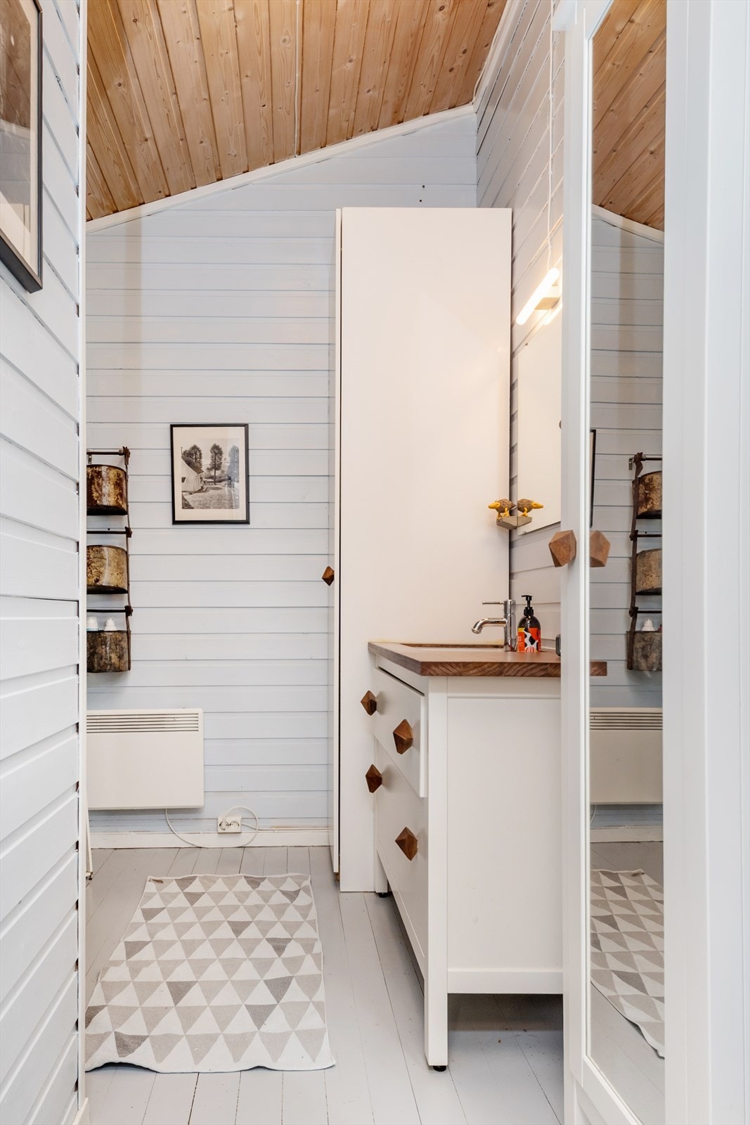 Badet har innredning med vask, trepanel på veggene og furugulv. Galleribilde