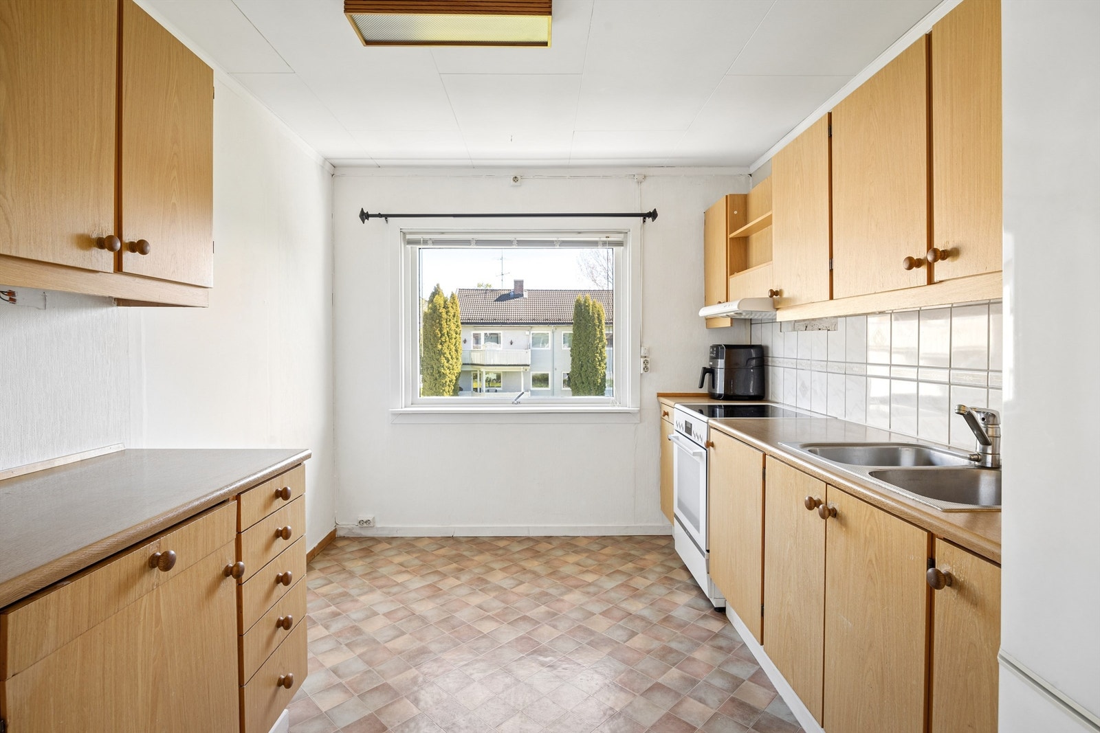Kjøkkeninnredning med glatte fronter og benkeplate med laminert overflate. Plass til frittstående komfyr og kjøleskap. Galleribilde