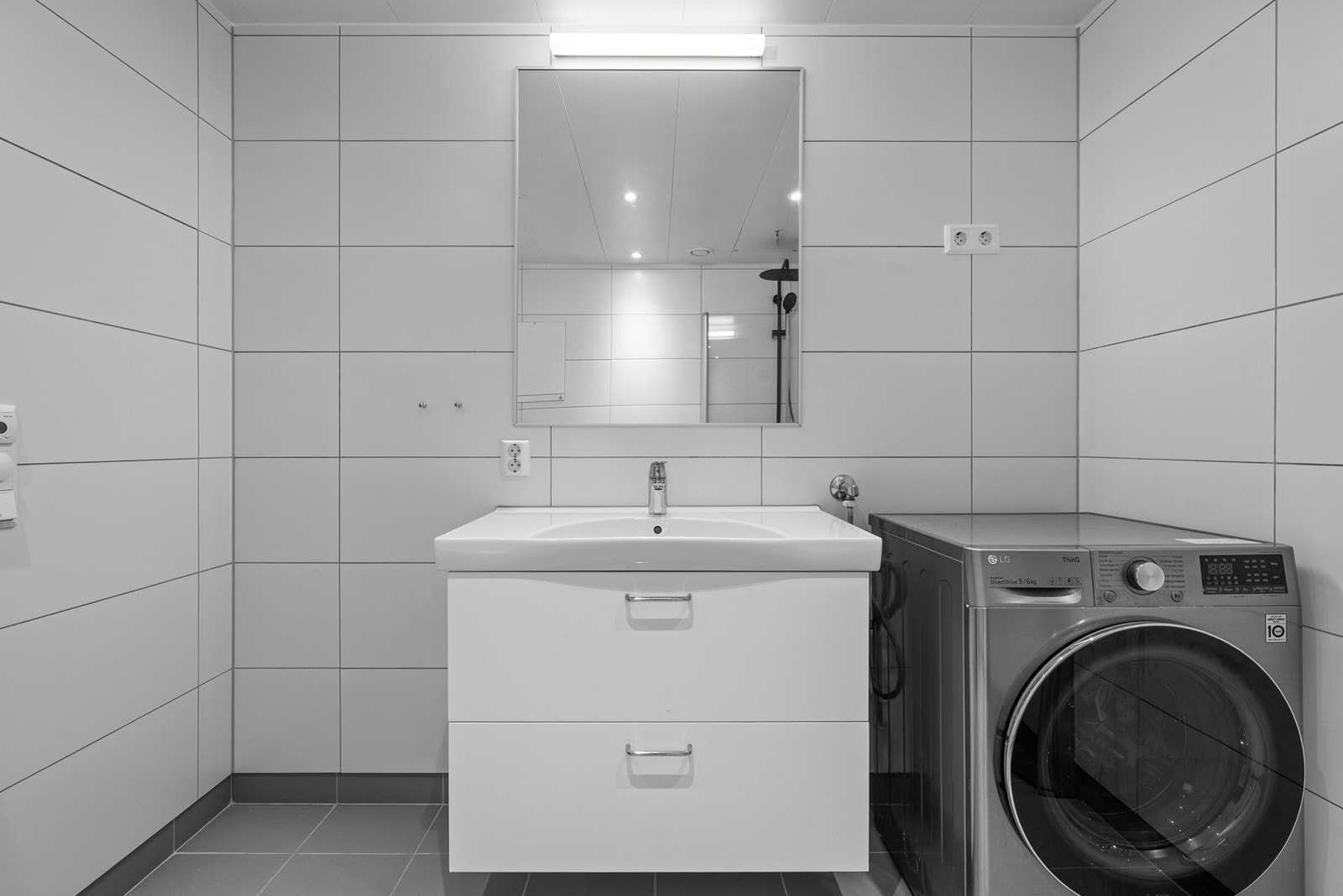 Badet har opplegg for vaskemaskin og en stilren servantinnredning med skuffer. Galleribilde
