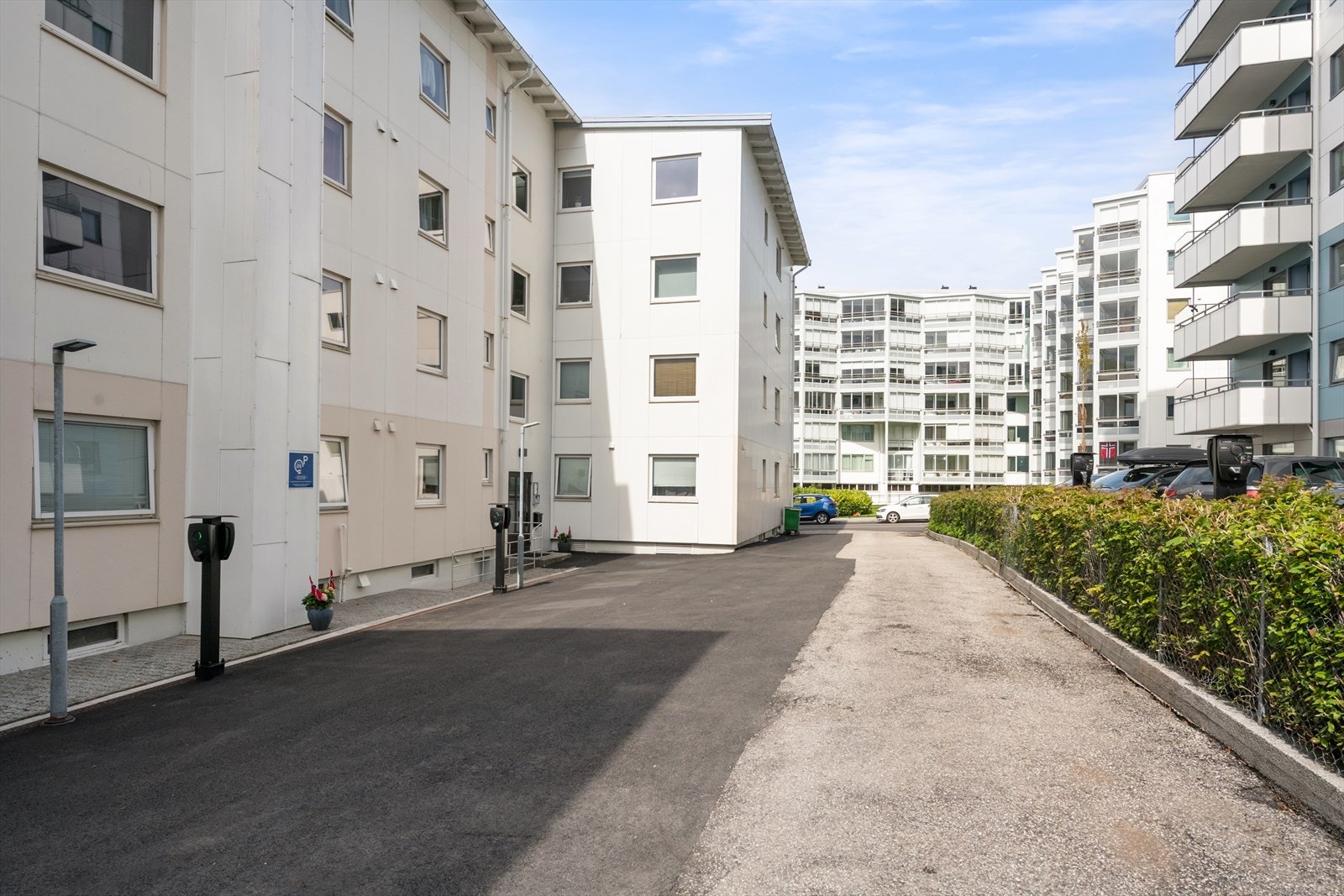 Tomten er opparbeidet med asfaltert adkomst, plener og hekk. Borettslaget har etablert elbil-ladere på eiendommen. Galleribilde