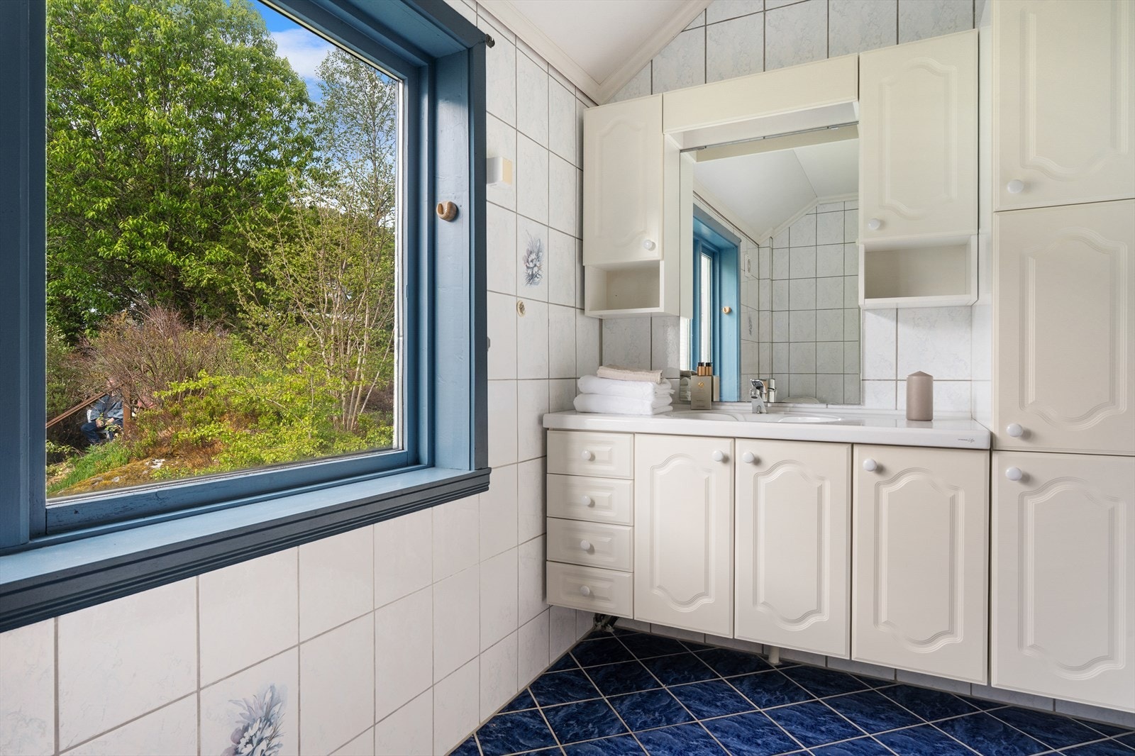 Badet er innredet med dusjhjørne, toalett og benkeskap med nedfelt servant samt speil med belysning over. Galleribilde