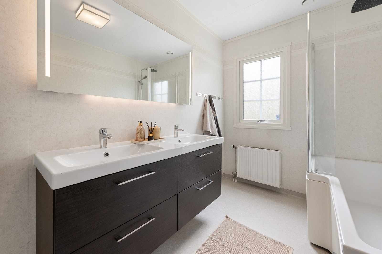Badet er innredet med dobbeltservant med skuffeseksjon, integrert speil med lys, toalett og badekar med dusjløsning (innredninger var nye i 2019). Galleribilde