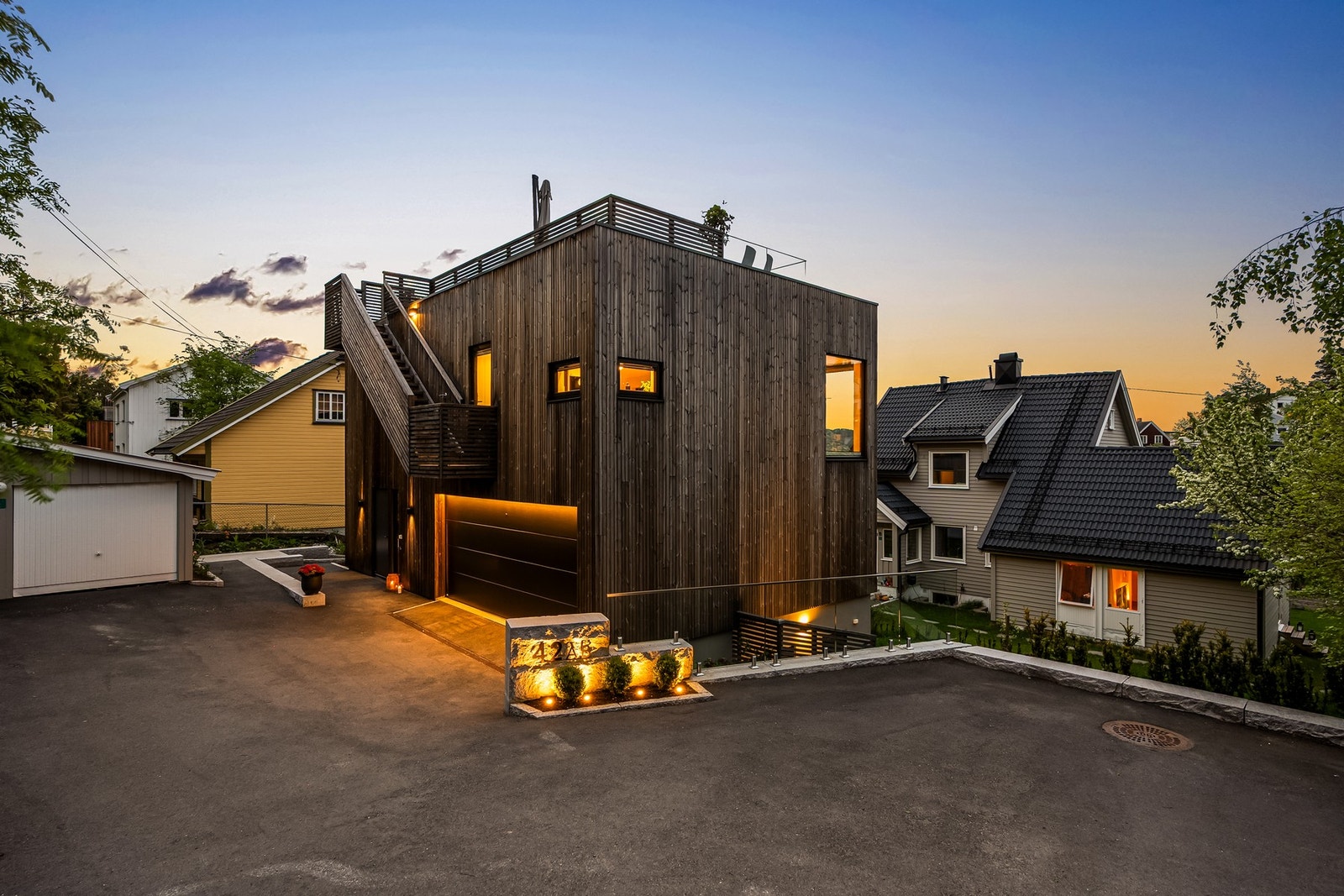 På fremsiden er det en romslig, asfaltert gårdsplass med plass for at barna leker. Gårdsplassen rammes inn med kantstein av granitt og rekkverk i glass. Praktisk og gjennomtenkt utebelysning. Galleribilde