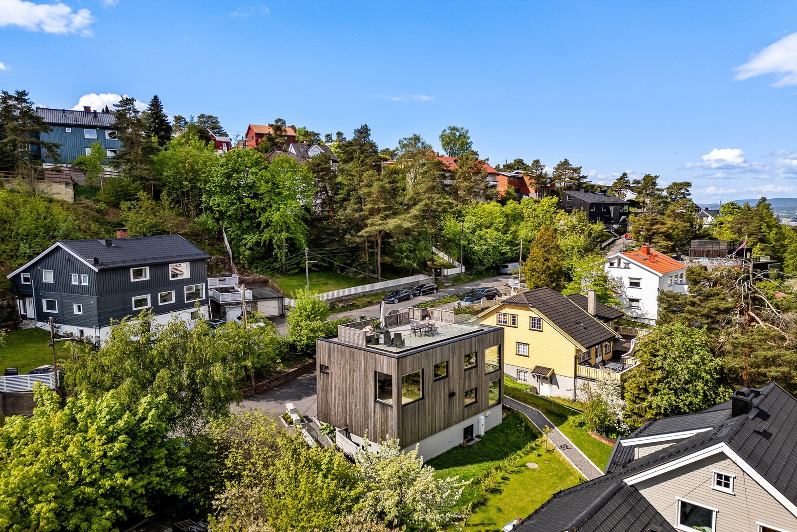Eneboligen fremstår med smakfulle materialvalg og høy standard. Boligen har en asfaltert gårdsplass på fremsiden og parkering i en integrert dobbelgarasje med elbillader. Galleribilde