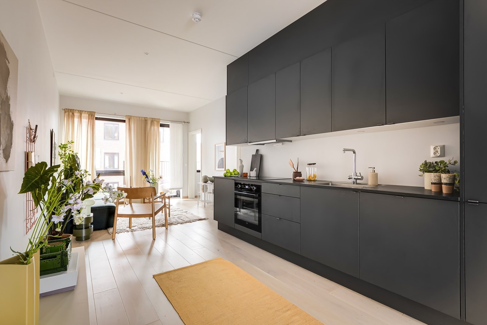 Stue og kjøkken ligger i en åpen løsning, som gjør boligen sosial og luftig. Kjøkkenet er integrert i vegg på en smakfull måte, og utgjør et stilrent møbel i seg selv. Galleribilde