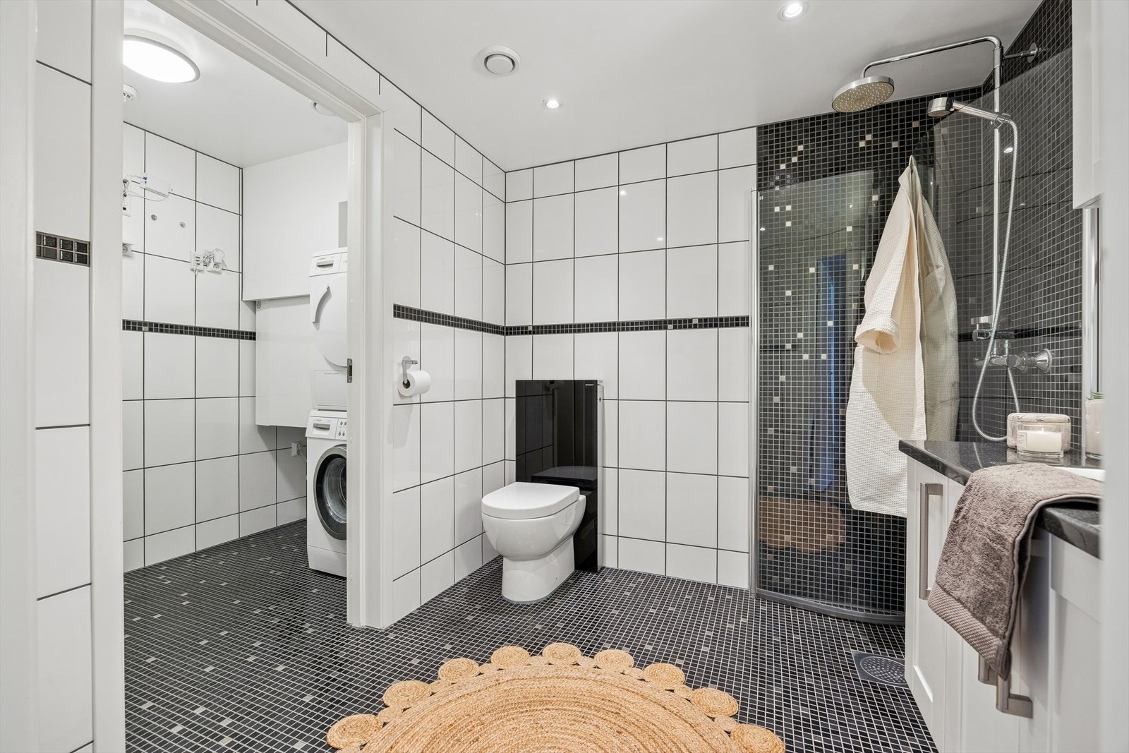 Badet er flislagt på både vegger og gulv, og har behagelig gulvvarme. Innredningen består av servant med opplyst speil, dusjhjørne og toalett. På vaskerommet er det opplegg og plass til både vaskemaskin og tørketrommel. Galleribilde