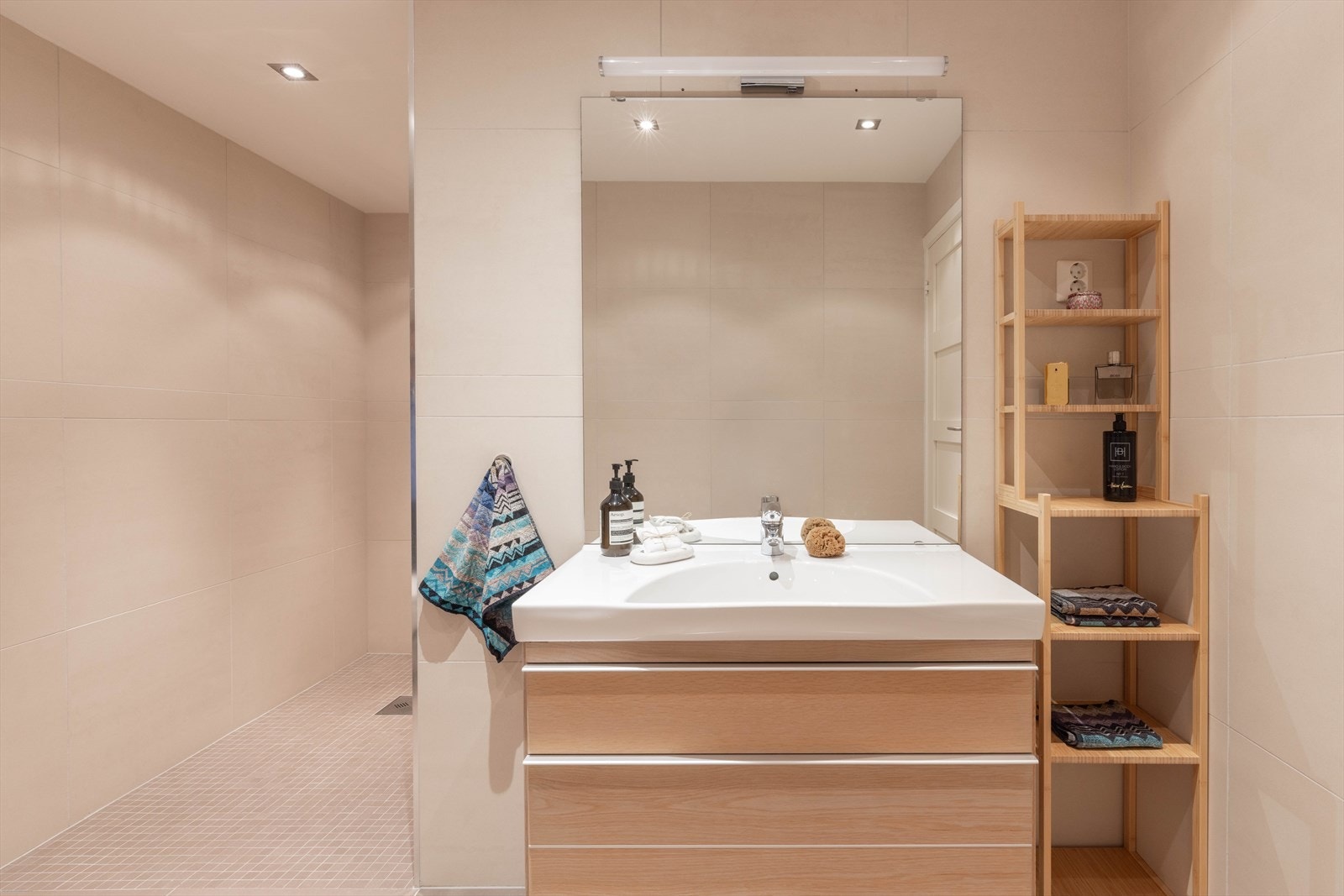 Underetasjens bad har inngang fra hallen. Badet er helfliset og er innredet med servant, stor dusjnisje og toalett. Galleribilde