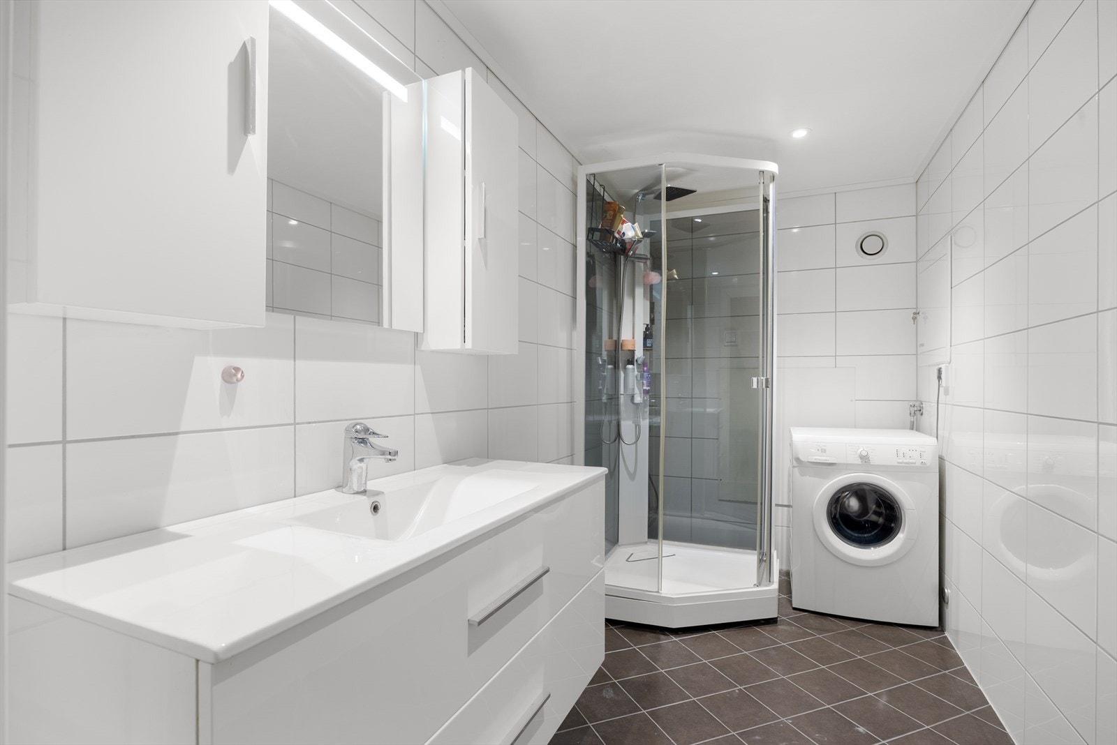 Badet ble rehabilitert i 2019 med flislagte overflater, servantinnredning og opplegg for vaskemaskin. Galleribilde