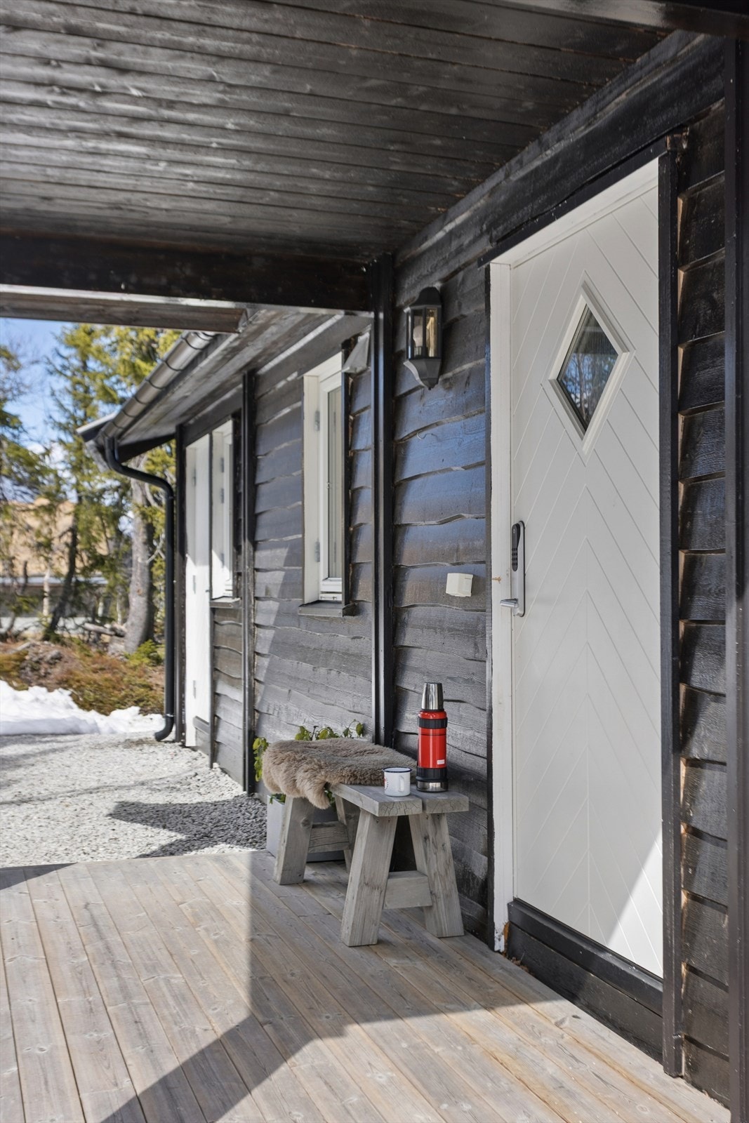 Overbygget inngangsparti med terrasse og malt hovedytterdør. Tilkomst til bod like ved siden av inngangspartiet. Galleribilde