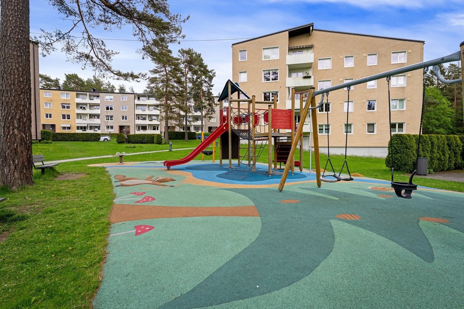 Store grøntarealer med plen, beplantning, sittegrupper og lekeplass. Galleribilde