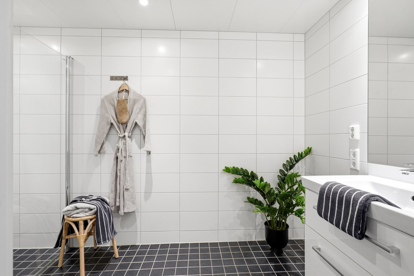 Badet er en prefabrikkert modul fra 2022 med flislagt gulv med varmekabler og fliser på veggene. Galleribilde