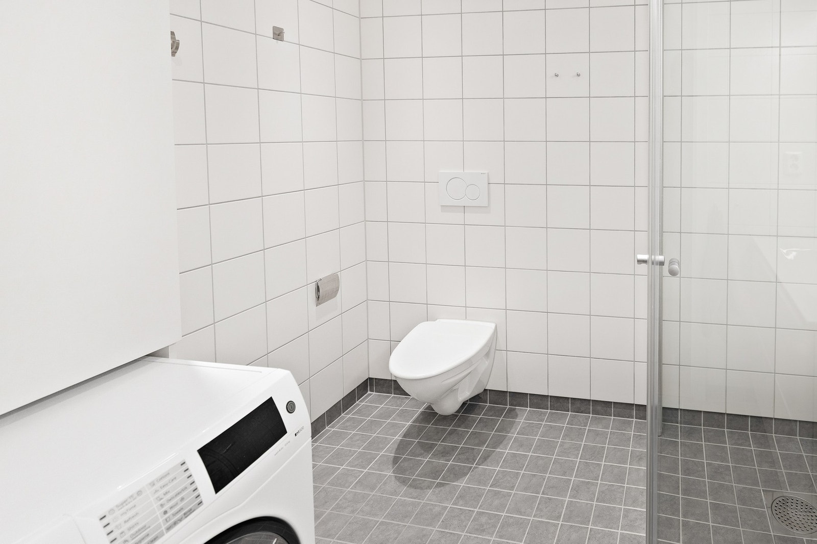 Badet har vegghengt toalett og praktisk opplegg for vaskemaskin. Galleribilde