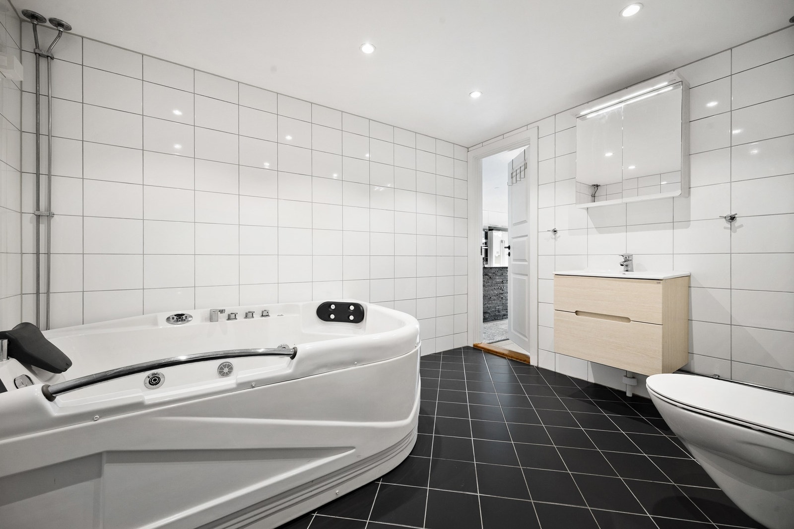 Badet er innredet med vegghengt servantinnredning med speilskap over servant. Videre er det vegghengt toalett, hjørneboblebadekar og dusjhjørne. Galleribilde