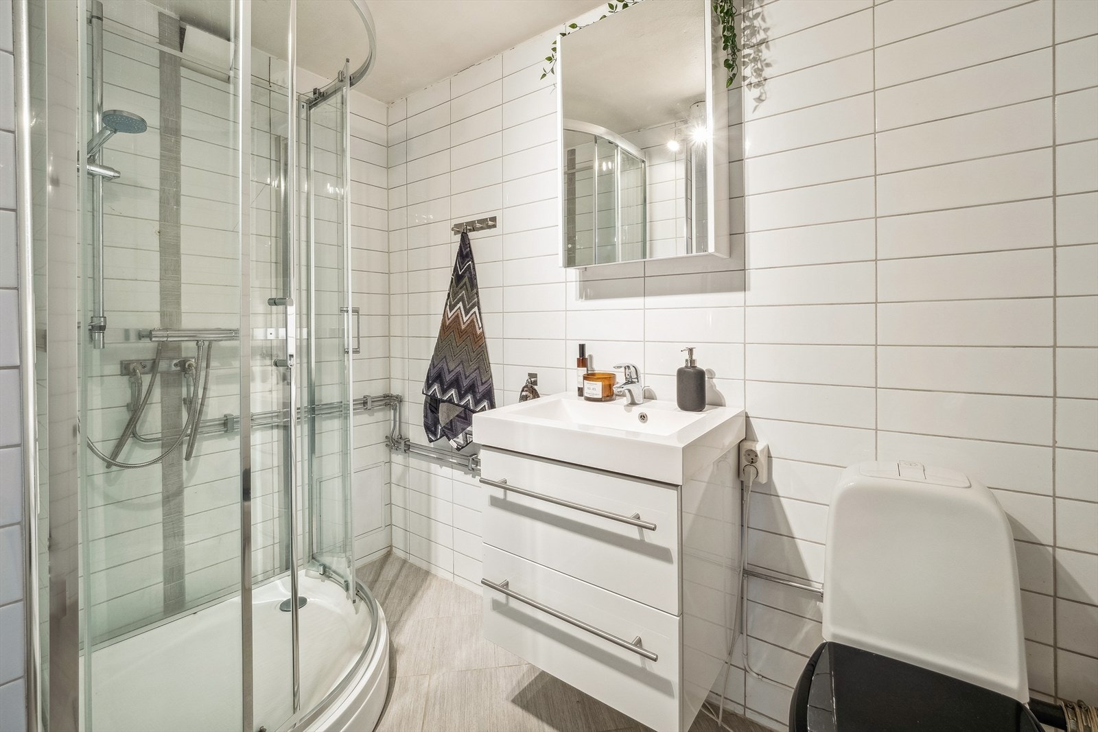 Leiligheten har to bad. Dette badet er utstyrt med dusjkabinett, servant med underskap og gulvmontert toalett. Galleribilde