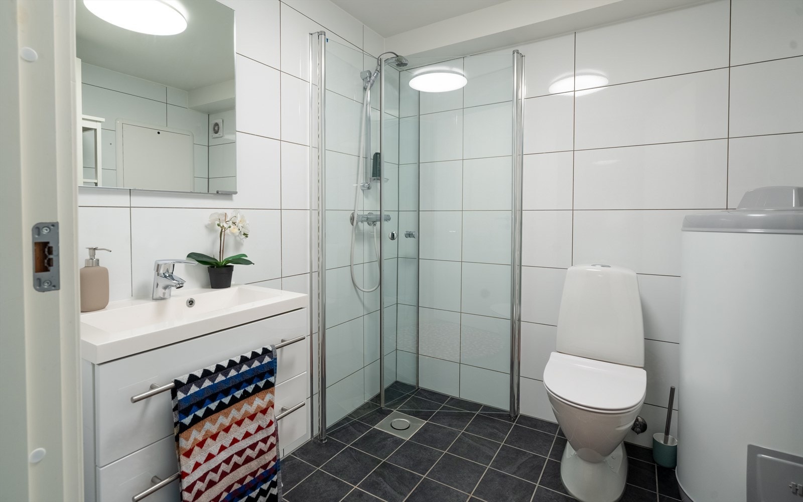 Helfliset bad med moderne innredning. Badet har toalett, dusjhjørne med foldbare glassvegger, hel servant og god lagringsplass i baderomsmøbel. Varmekabler i gulv som bidrar til økt komfort i hverdagen. (Ikke godkjent for varig opphold). Galleribilde
