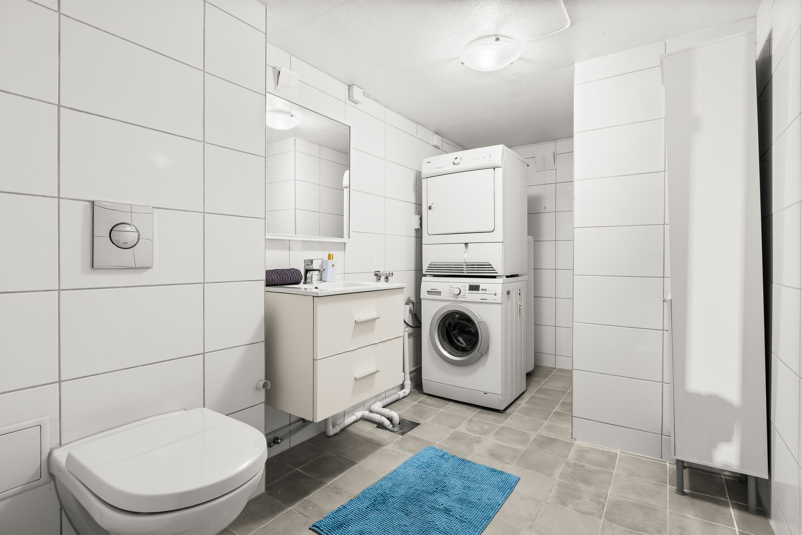 Romslig og flislagt bad med varmekabler i gulv. Badet har opplegg for vaskemaskin og tørketrommel. Galleribilde