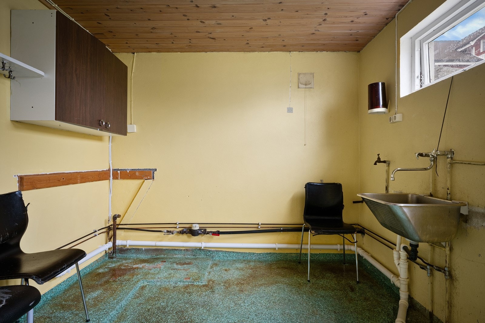 Praktisk vaskerom i kjelleren med utslagsvask i stål og opplegg for vaskemaskin. Galleribilde