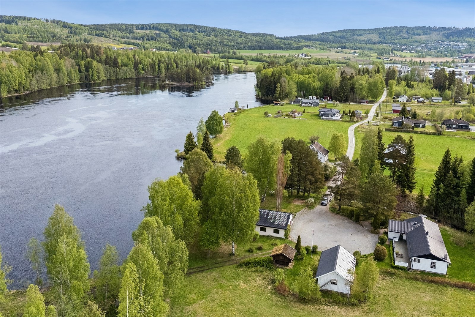 Oversiktsbilde som viser eiendommens plassering i landskapet, med nærhet til både skog og vann. Galleribilde