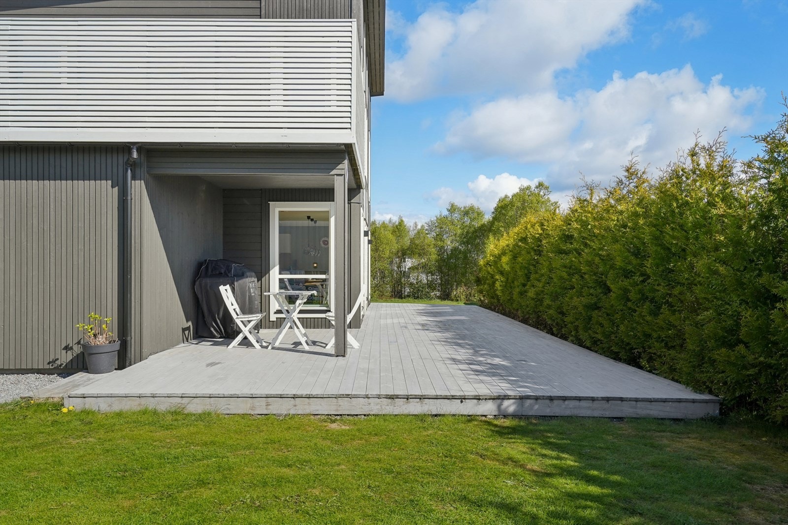 Terrassen går over i plenarealer og en lettstelt hage, avgrenset med hekk. Galleribilde