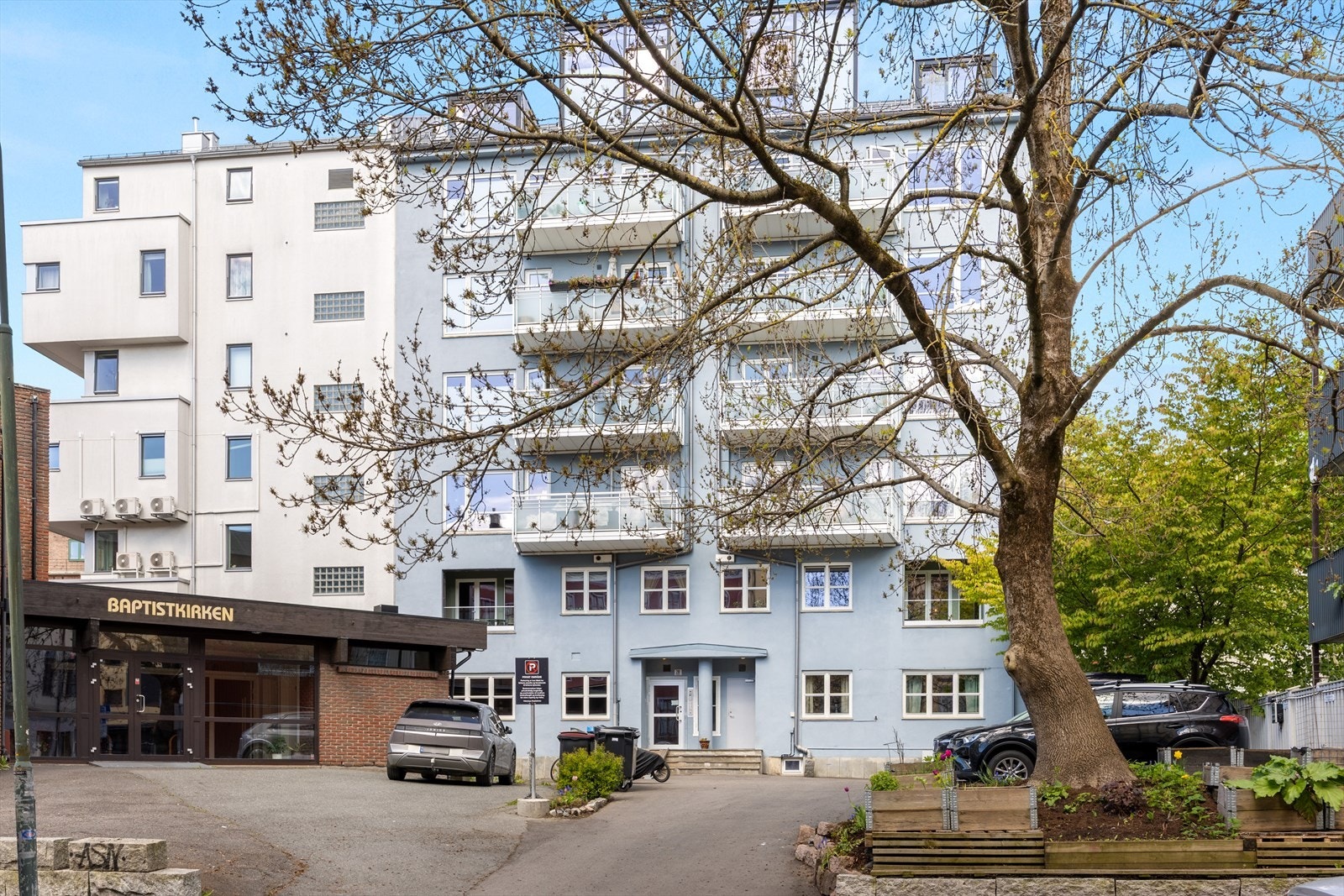 Leiligheten ligger i 7. og øverste etasje i et boligbygg med heis og har parkeringsplass rett utenfor inngangspartiet. Det er plantekasser under treet hvor beboerne kan dyrke selv. Galleribilde